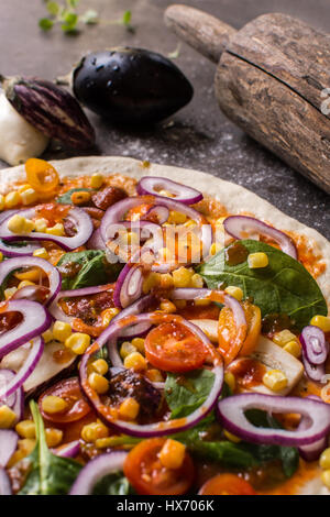 Materie impasto per pizza e perno di rotolamento con ingredienti. Pizza italiana rendendo concetto. Foto Stock
