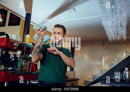 Il barista, barista salviette di lavoro il vetro con un panno in una posizione di riposo Foto Stock