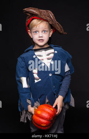 Little boy in costume di halloween di pirata in posa con la zucca su sfondo nero. Ritratto in studio Foto Stock