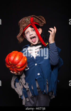 Little boy in costume di halloween di pirata in posa con la zucca su sfondo nero. Ritratto in studio Foto Stock