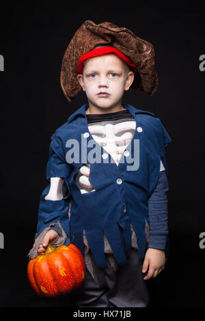 Little boy in costume di halloween di pirata in posa con la zucca su sfondo nero. Ritratto in studio Foto Stock