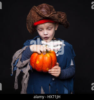 Little boy in costume di halloween di pirata in posa con la zucca su sfondo nero. Ritratto in studio Foto Stock