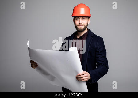 Ritratto di un architetto builder studiando piano di disposizione delle camere, serio ingegnere civile che lavora con i documenti sul sito in costruzione. Foto Stock