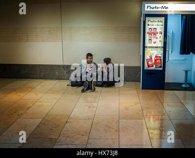 Due persone mangiare il pranzo sul pavimento accanto a una foto-me istant Photo Booth in Cambridge shopping centre Foto Stock