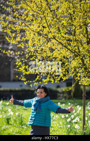 Una donna di fronte di alberi in fiore in James Park, Londra. Foto Stock