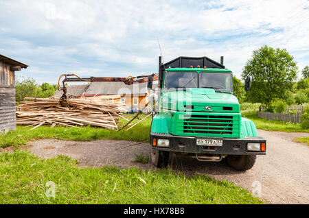 Novgorod, Russia - Luglio 25, 2016: Log manipolatore idraulica legname scaricato dal carrello in giorno di estate Foto Stock