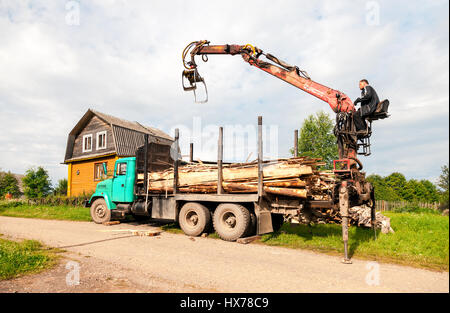 Novgorod, Russia - Luglio 25, 2016: Log manipolatore idraulica legname scaricato dal carrello in giorno di estate Foto Stock