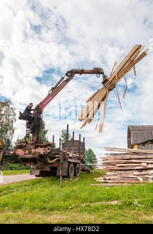 Novgorod, Russia - Luglio 25, 2016: Log manipolatore idraulica legname scaricato dal carrello in giorno di estate Foto Stock