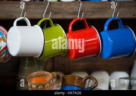 Colorato in ferro zincato mug appesa in un cafe Foto Stock