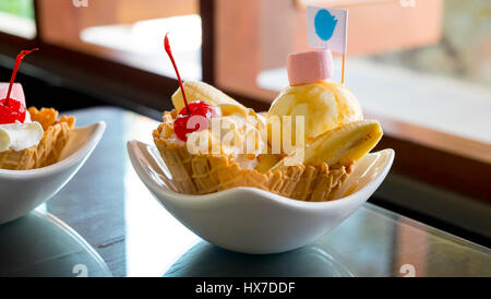 Gelato alla vaniglia in waffel e panna montata e banana e ciliegia Foto Stock