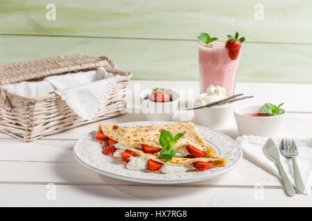 Pancake con fragole fresche sul vecchio tavolo in legno Foto Stock