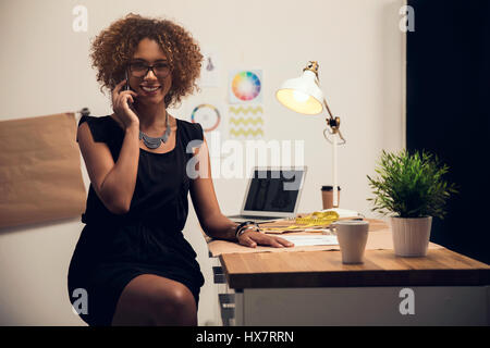 Una giovane designer di moda sul suo atelier di effettuare una chiamata Foto Stock