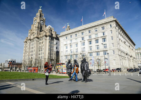 I turisti pongono per fotografie con le statue della famosa in tutto il mondo 1960 Gruppo, i Beatles. Le statue del famoso gruppo di Liverpool i Beatles situat Foto Stock