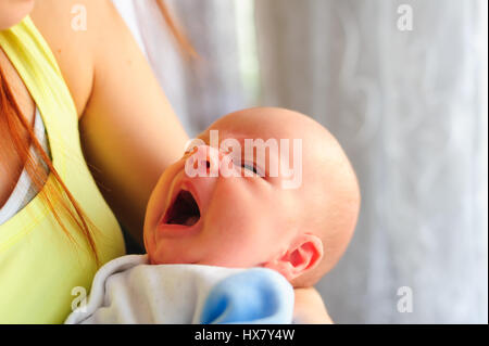 Da più di un mese il bambino a sbadigliare mentre si trattiene la sua mano delle madri. Foto Stock