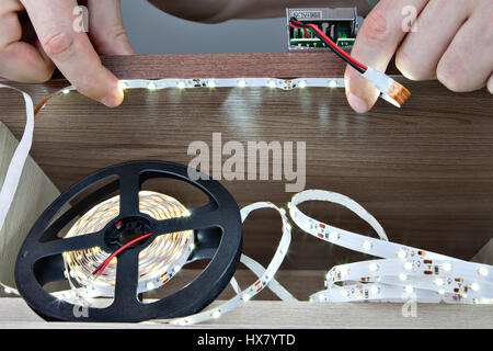 Carpenter stick nastro led all'interno di mobili, close-up di mani. Foto Stock