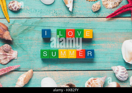 Io amo estate scritto in colorate dei blocchi di legno su un sfondo di legno con una stella di mare Foto Stock