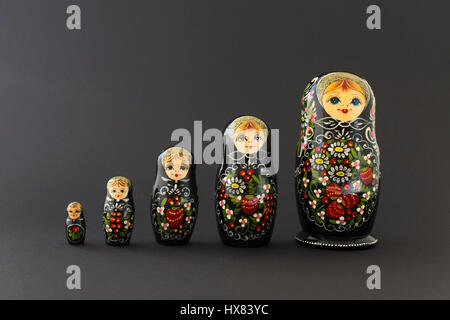 Bella black russian nesting dolls (matrioska bambole) con bianco, verde e rosso dipinto nella parte anteriore di uno sfondo scuro Foto Stock