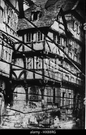 Questa immagine storica della "Haus mit den Knaggen" di Marburgo risalente a prima del 1859 mostra un tipico esempio di architettura medievale in Germania. Le caratteristiche distintive includono l'uso di staffe in legno e il ripido tetto tipico delle case in legno della regione. Foto Stock