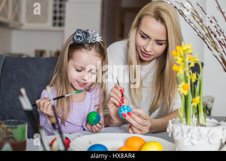 Pasqua, famiglia, vacanza e concetto di bambino - close up della bambina e madre colorare le uova per la Pasqua Foto Stock