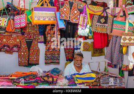 KUTCH, Gujarat, India - 27 dicembre 2016: un artigianato non identificato fornitore nel suo tradizionale street negozio di vendita colorati articoli da ricamo. Foto Stock