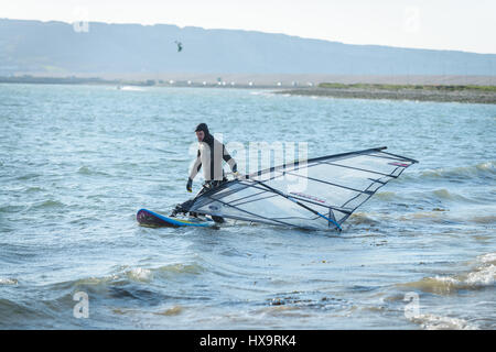 Portland Harbour, Dorset, Regno Unito. Il 26 marzo 2017. Un uomo prepara il suo wind surf di bordo su un croccante di Ventoso giornata soleggiata al Portland Harbour su Mothering Domenica. © Dan Tucker/Alamy Live News Foto Stock