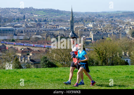 Bath, Regno Unito. 26 Mar, 2017. Con la città di Bath dietro di loro due corridori sono ritratte in esecuzione nella campagna Deluxe Doubles hill come essi approfittare del bel tempo e il caldo sole primaverile. Credito: lynchpics/Alamy Live News Foto Stock