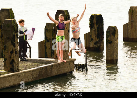 Aberystwyth, Wales UK, madri giorno, domenica 26 marzo 2017 UK meteo: Kids il salto in mare al largo del molo di legno in un caldo pomeriggio in una giornata di sole e cielo azzurro in Aberystwyth sulla West Wales coast. Photo credit: keith morris/Alamy Live News Foto Stock