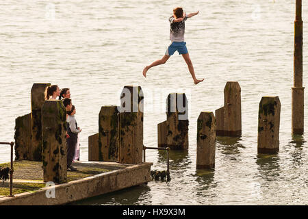 Aberystwyth, Wales UK, madri giorno, domenica 26 marzo 2017 UK meteo: Kids il salto in mare al largo del molo di legno in un caldo pomeriggio in una giornata di sole e cielo azzurro in Aberystwyth sulla West Wales coast. Photo credit: keith morris/Alamy Live News Foto Stock