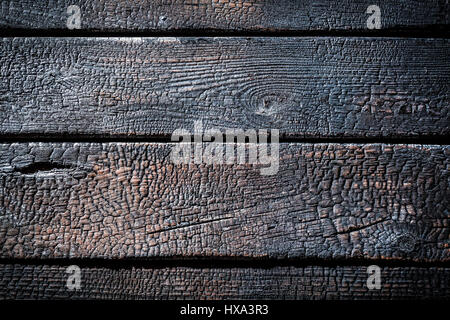 Primo piano di bruciato staccionata in legno come sfondo Foto Stock