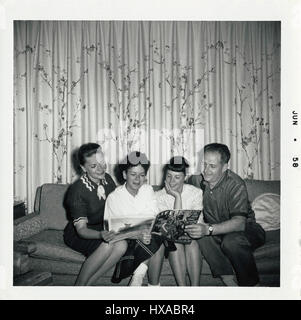 Famiglia Americana leggendo la rivista Life nel 1958. Foto Stock
