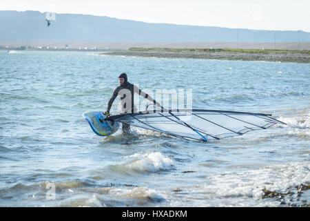 Portland Harbour, Dorset, Regno Unito. Il 26 marzo 2017. Un uomo prepara il suo wind surf di bordo su un croccante di Ventoso giornata soleggiata al Portland Harbour su Mothering Domenica. © Dan Tucker/Alamy Live News Foto Stock