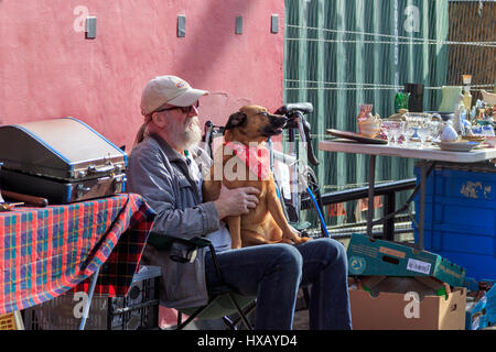 Stallholder a Glasgow il famoso Barras aria aperta e street market, seduti al sole come accarezzare il suo cane. Glasgow. Scozia.UK Foto Stock