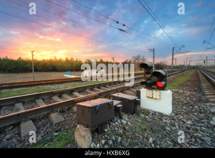 Stazione ferroviaria con semaforo e bellissimo luminoso cielo nuvoloso al tramonto. Colorato paesaggio industriale. Ferrovia. Piattaforma ferroviaria con semaforo Foto Stock