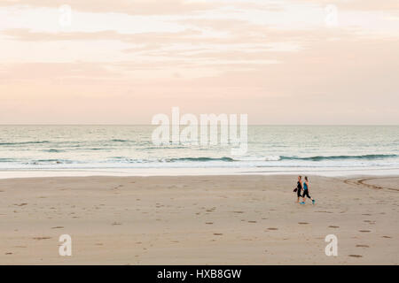 Le donne a piedi lungo le sabbie della spiaggia di Bargara al tramonto, Bundaberg, Queensland, Australia Foto Stock