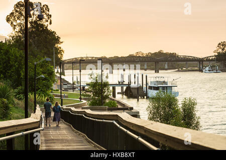 Giovane a piedi lungo la passeggiata lungo il fiume al tramonto. Bundaberg, Queensland, Australia Foto Stock