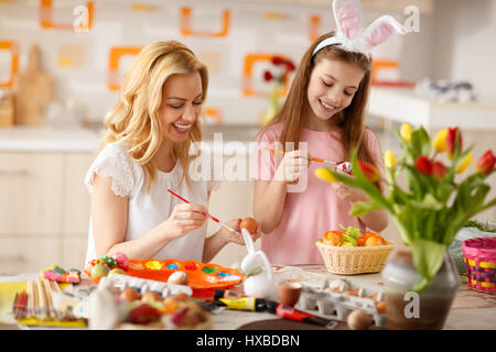 Madre e figlia di pittura delle uova di Pasqua in cucina Foto Stock