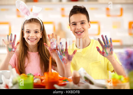 Sorridente un ragazzo e una ragazza mostra le mani di pittura con le uova di colore Foto Stock