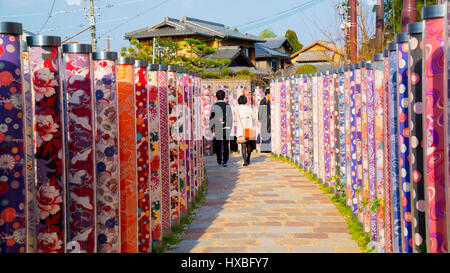 Coppia giovane che attraversa la lampada colorata decorazione posti sulla piattaforma ferroviaria di Kyoto Foto Stock