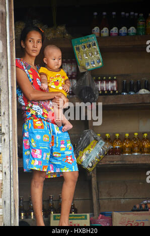 Una donna che tiene il suo bambino nella porta di un negozio nel villaggio di Makyone Galet, Lampi National Marine Park, Myeik arcipelago, Myanmar Foto Stock