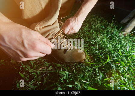 Primo piano di legatura di scarpe da escursionismo stand su erba verde. L'uomo legare il suo laccio Foto Stock