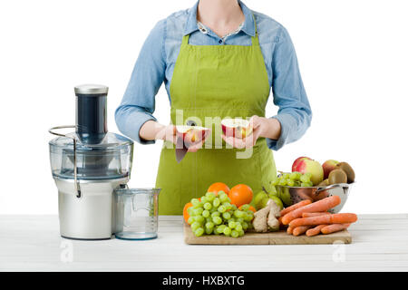 Anonimo donna che indossa un grembiule, la preparazione di succhi di frutta freschi utilizzando moderne spremiagrumi elettrico, uno stile di vita sano concetto su sfondo bianco Foto Stock