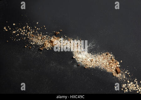 Briciole di pane con farina rappresentati su sfondo nero dopo la cottura e la cottura del pane fresco. Vista superiore o tavola nera in cucina. Industria alimentare concep Foto Stock