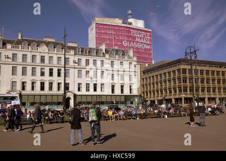 George Square nel centro città filld con ditizenx e turisti che si godono il sole unseasonable Foto Stock