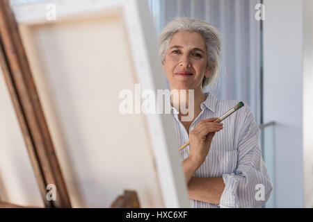 Ritratto fiducioso donna matura la pittura alla tela su cavalletto