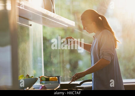 Donna versando olio in padella sulla stufa in cucina Foto Stock