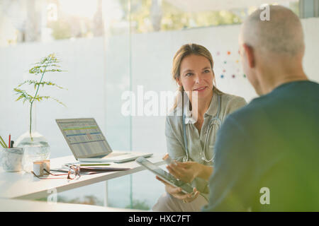 Medico donna che mostra digitale compressa al paziente di sesso maschile nell'ufficio del medico Foto Stock