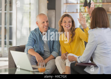 Felice coppia alta fiving advisor finanziario in salotto Foto Stock