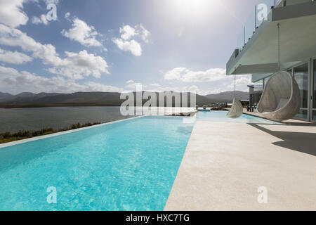 Tranquilla soleggiata e lusso moderno home vetrina patio esterno con piscina infinity e vista oceano Foto Stock