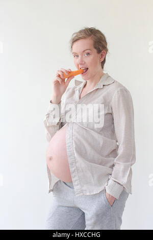 Donna incinta di mangiare una carota Foto Stock