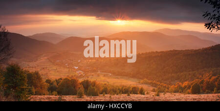 Splendida serata di montagna paesaggio. Sole illuminano misty scena della montagna. Bellissimo sfondo d'autunno. Nizza tema Halloween. Alberi colorati in mountai Foto Stock